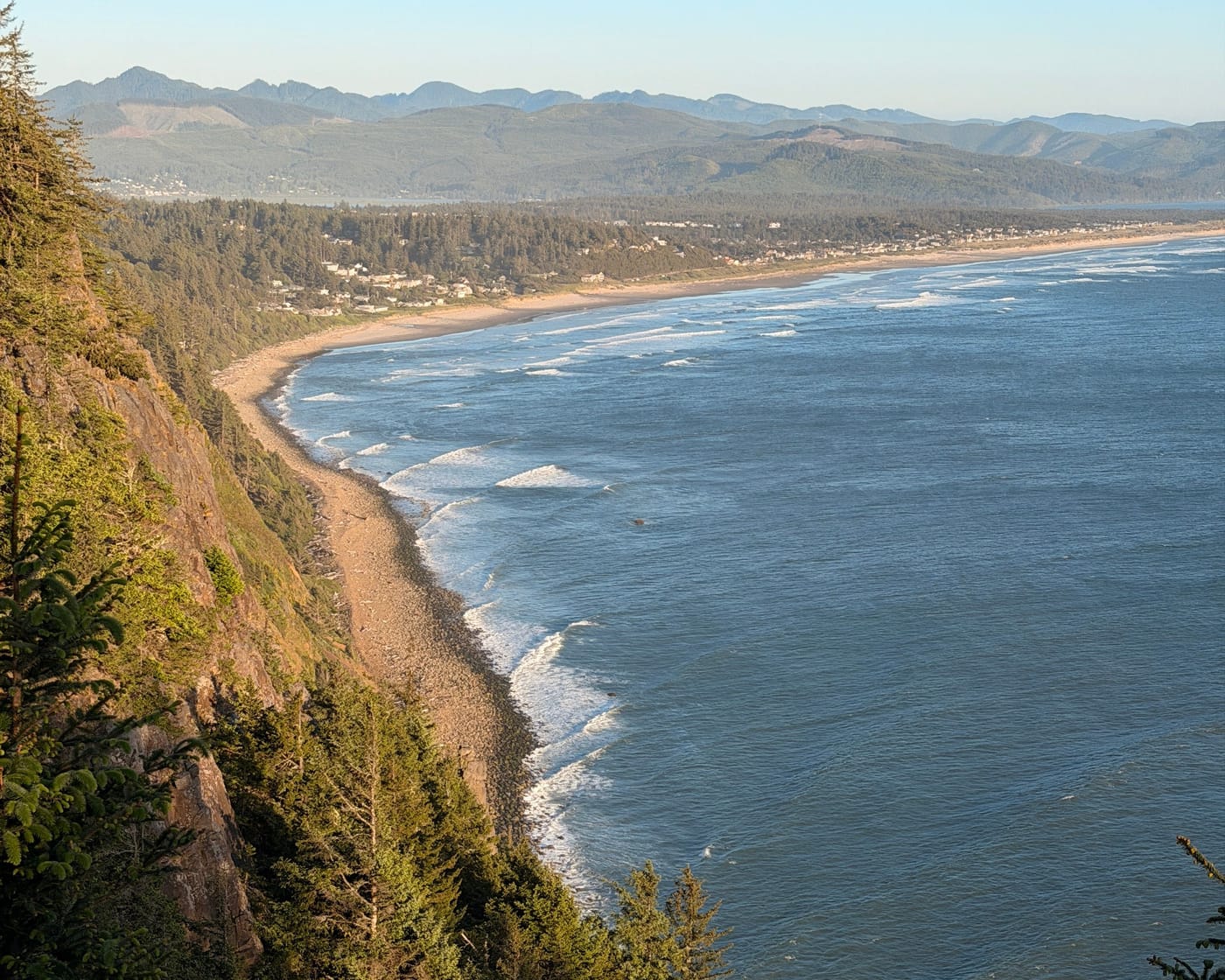 View from a forested headland over a long sandy beach and the Pacific Ocean